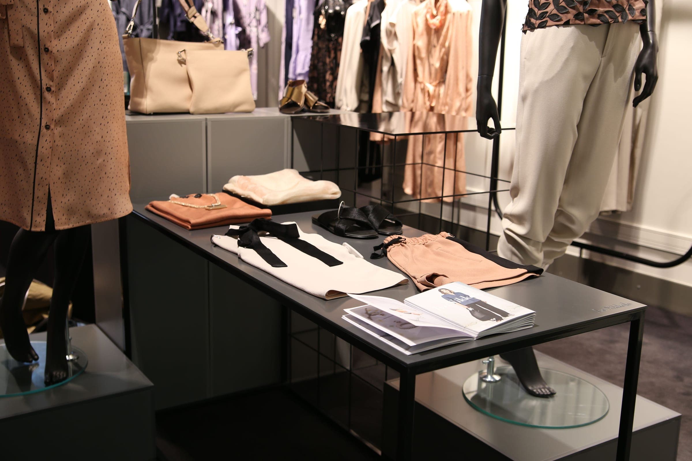 Fashion boutique with a dark display table and garments on rails